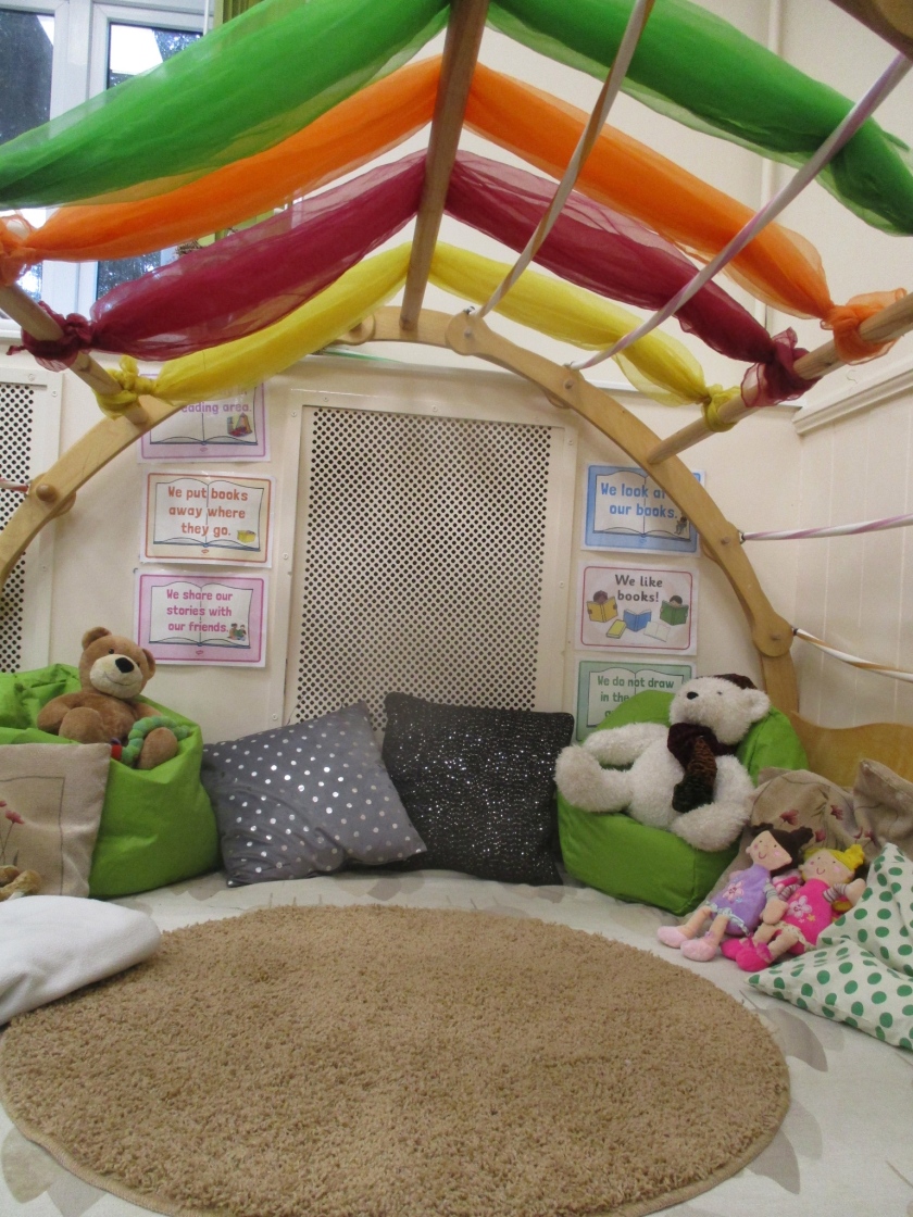 A semi domed reading area, replete with coloured cushions and soft toys.
